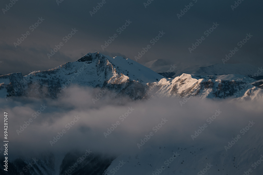 Rocky mountains covered with snow stand in the dark