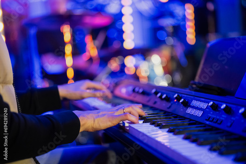 Musician pianist playing keyboard digital piano with blue blurred background with lights in concert photo