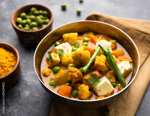 mix vegetable curry indian main course recipe contains carrots, cauliflower, green peas and beans, baby corn, capsicum and paneer cottage cheese with traditional masala and curry, selective focus photo