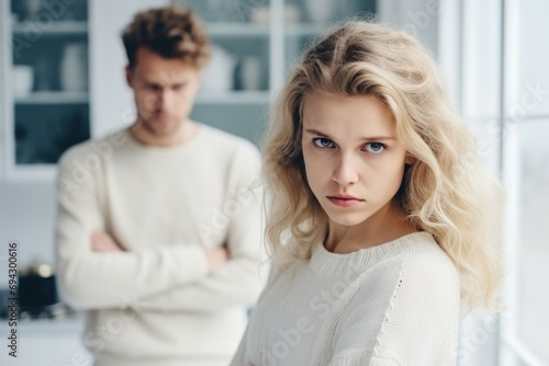 Upset young blonde woman and man argument, сlose up sad wife looks at camera in front and husband standing behind quarrel at home. Family conflict, crisis, psychological abuse, relationships concept