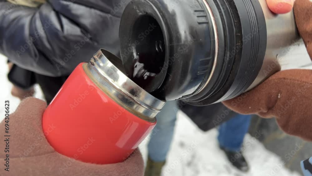 drinking hot mulled wine in cold in winter people women drinking delicious drink steam gloves close-up hands people pour wine tea into thermos warm up walk Picnic. Walk in winter on excursion drinking hot mulled wine in cold in winter people women drinking delicious drink steam gloves close-up hands people pour wine tea into thermos warm up walk Picnic. Walk in winter on excursion