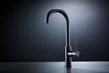 Close-up of modern black matte kitchen faucet, black acrylic stone countertop, stainless steel built-in sink against the background of black wall with spot lighting. Copy space.