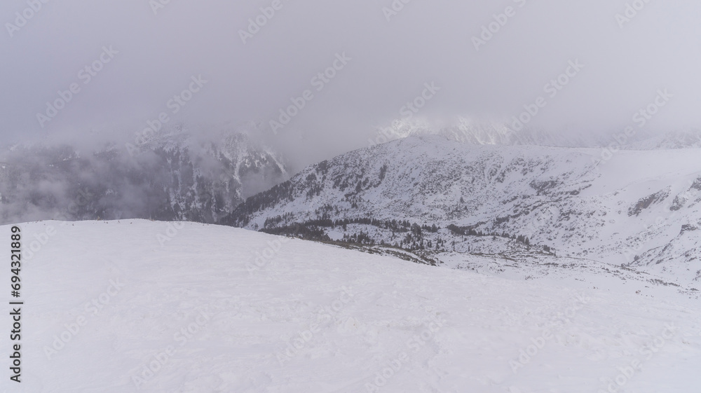 The white snowy peaks of Pirin covered with snow and fog. Snowy weather conditions for winter sports and tourism. Bansko Alpine Ski Resort, Bulgaria.
