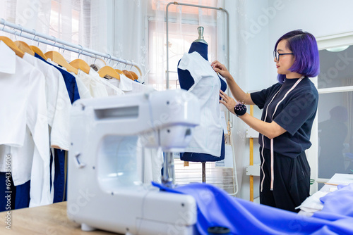 Fashionable freelance dressmaker is pinning her marking muslin for new dress by pinning to mannequin while working in the artistic workshop studio for fashion design and clothing business industry photo