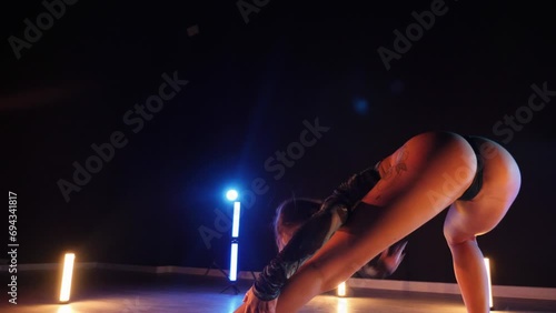 Sexy woman dancing a seductive dance. A dancer girl with a big ass dances erotically in a dark hall. Twerk, high heels, striptease photo