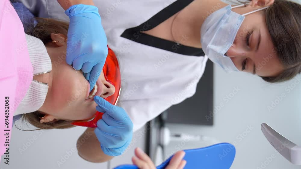 Female patient sitting in dental chair while dentist demonstrates to