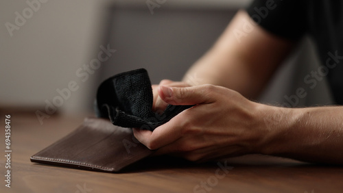 man cleaning leather wallet on wood table photo