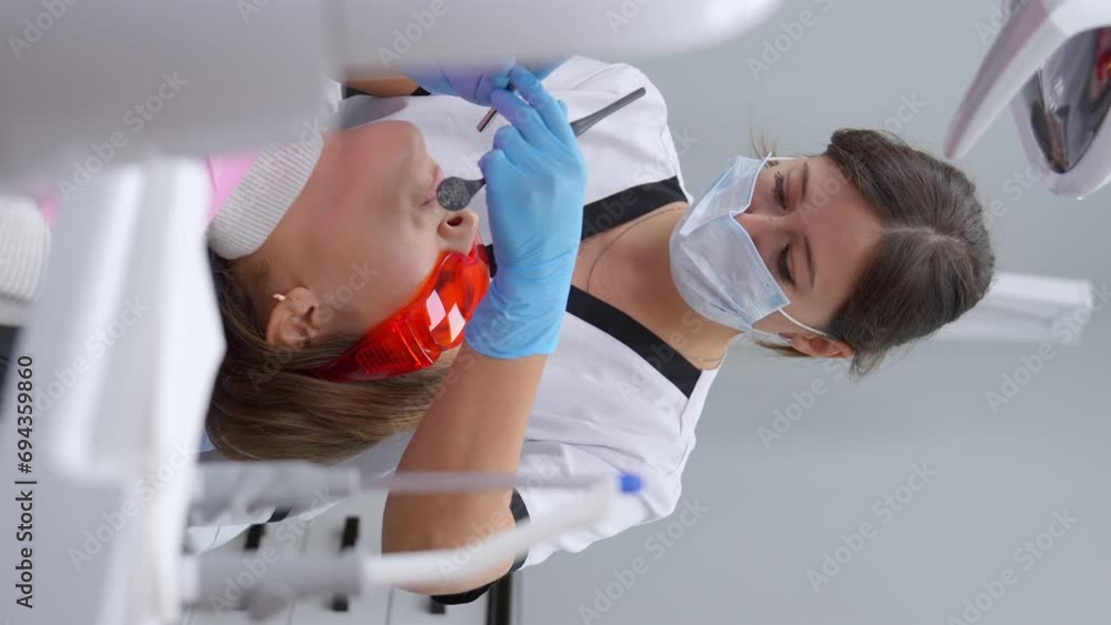 Female dentist treating patient's teeth. Dental Treatment in Modern Dentistry. Close-up of patient in dental chair during canal filling procedure . Medicine Healthcare. Vertical video Female dentist treating patient's teeth. Dental Treatment in Modern Dentistry. Close-up of patient in dental chair during canal filling procedure . Medicine Healthcare. Vertical video
