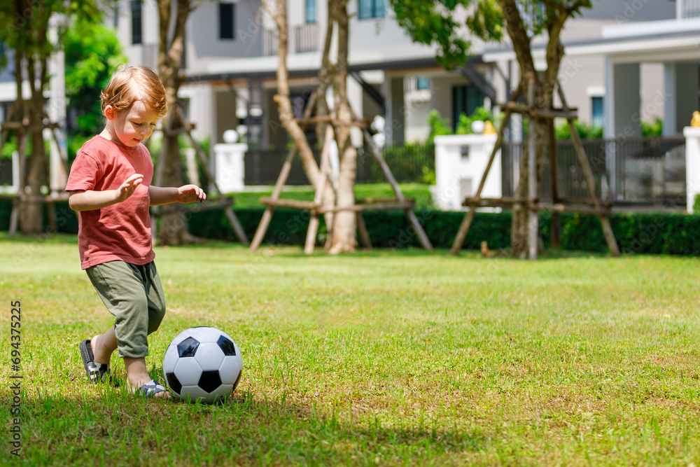 My son enjoys playing football in the backyard. Happy little child in nature in the park