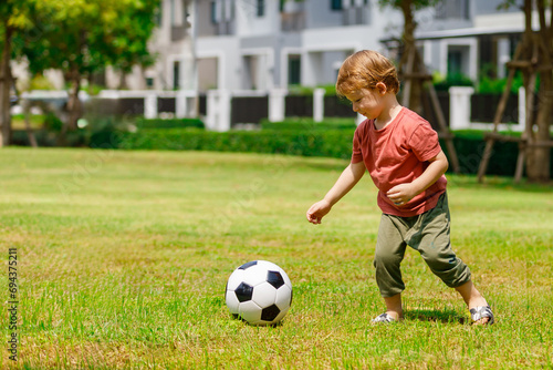 My son enjoys playing football in the backyard. Happy little child in nature in the park © atitaph