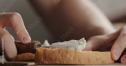 spread cream cheese on fresh ciabatta slice on olive board closeup