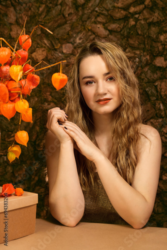 Girl with fesalis. A girl and a natural bouquet of orange dried flowers. Girl in archaic natural style. The girl and the historical primordial image.