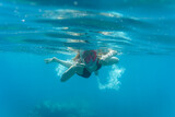 Chica haciendo snorkel. Saludando a cámara bajo el agua. Pulgares arriba.