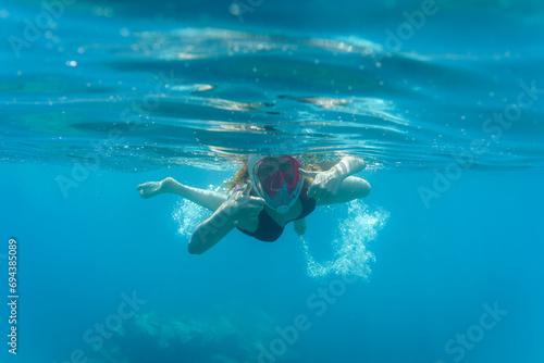 Chica haciendo snorkel. Saludando a cámara bajo el agua. Pulgares arriba.