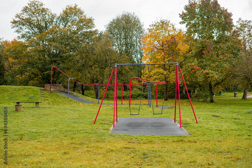 Swing set in a public park of a neighborhood in England during autumn season Swing set in a public park of a neighborhood in England during autumn season