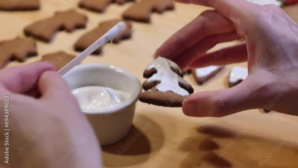 A closeup clip of a housewife decorating freshly baked home-made Christmas gingerbread cookies with white icing A closeup clip of a housewife decorating freshly baked home-made Christmas gingerbread cookies with white icing