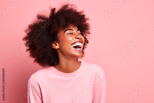 Close-up portrait of happy girl with big smile and afro hairstyle. Smiling dark skinned beautiful woman. Pink background.