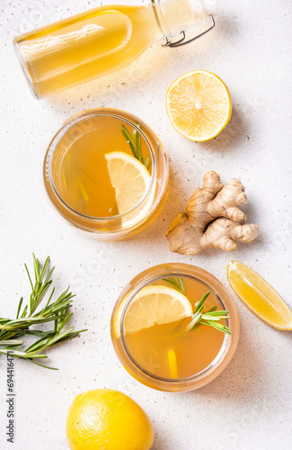 Preparation of refreshing kombucha with lemon and ginger, garnished with rosemary, flat lay, vertical orientation