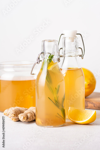 Homemade kombucha with lemon slices and ginger, bottled, vertical orientation, light background