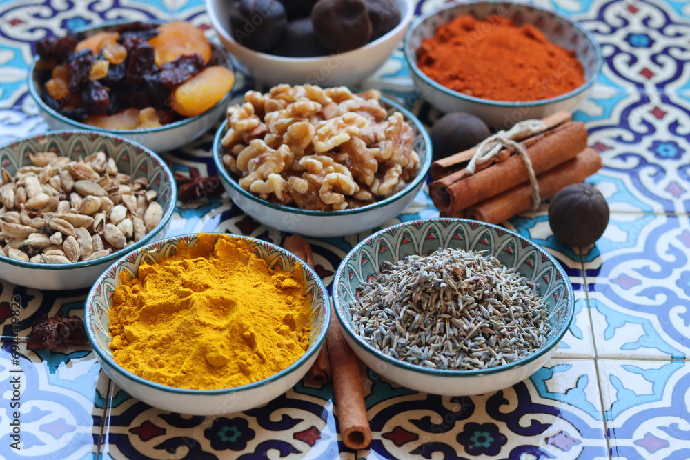 Spices and herbs in bowls on traditional Moroccan blue tiles background. 