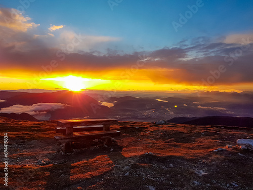 Panoramic sunrise view from summit Dobratsch on Julian Alps and Karawanks in Austria, Europe. Silhouette of endless mountain ranges with orange and pink colors of sky. Jagged sharp peaks and valleys © Chris