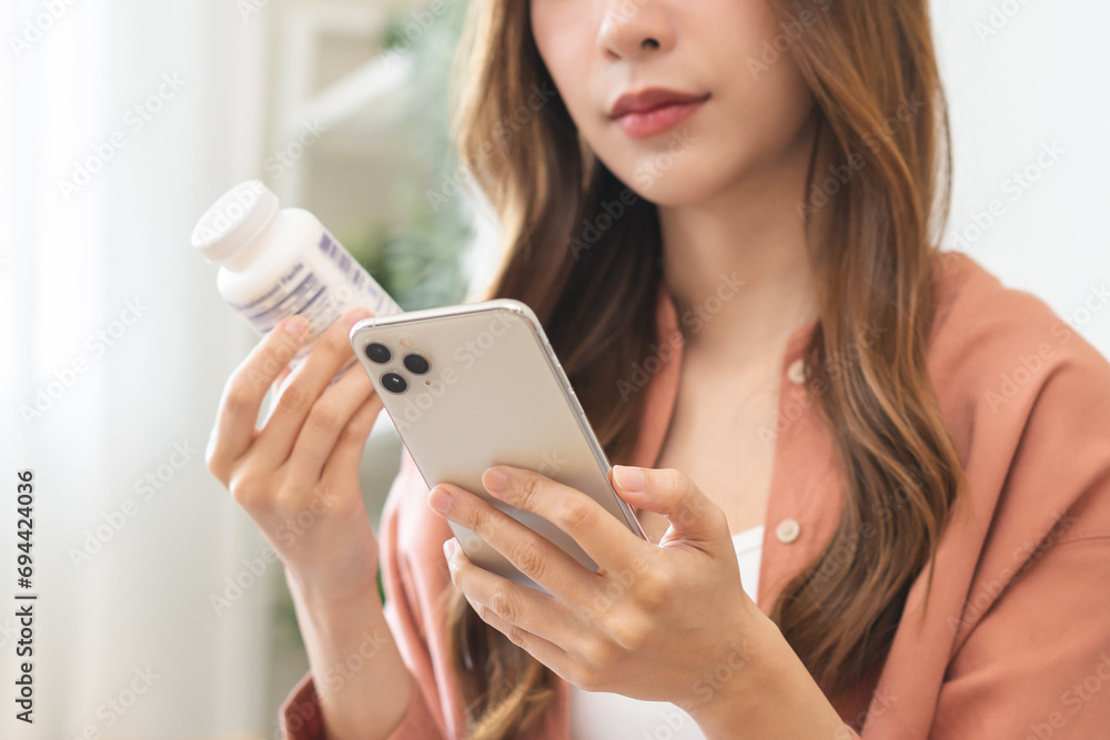 Health care asian young woman using smart phone for reading, searching prescription on bottle medicine, pill label text about information online, instructions side effects, pharmacy medicament concept - obrazy, fototapety, plakaty 