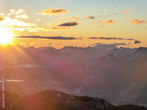 Panoramic sunrise view from Dobratsch on Julian Alps and Karawanks in Austria  Europe. Silhouette of endless mountain ranges. Lake Woerthersee  lake Woerth  surrounded by mysterious haze and fog