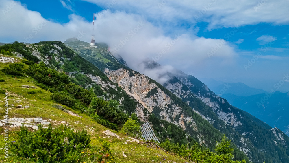 Hiking trail leading to mountain peak Dobratsch, Villacher Alps, Carinthia, Austria, Europe. Alpine meadow along the way to the radio tower on top. Panoramic view of hills and mountains. Wanderlust