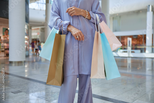 Closeup cropped shot of fashionable mature woman holding shopping bags