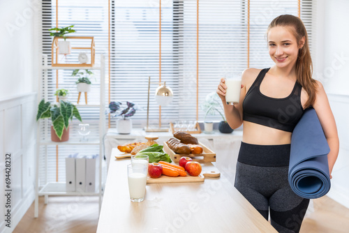 Attractive fitness  caucasian woman finishing workout and drinking protein milk shake vitamins after training at home. Bodybuilding. Healthy lifestyle.