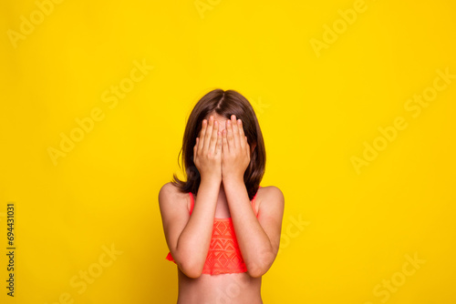 child girl covers her face with hands. little girl hide face behind hands. See nothing concept. photo