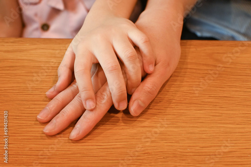 Child hold mother hand on table, giving support, courage. warm family