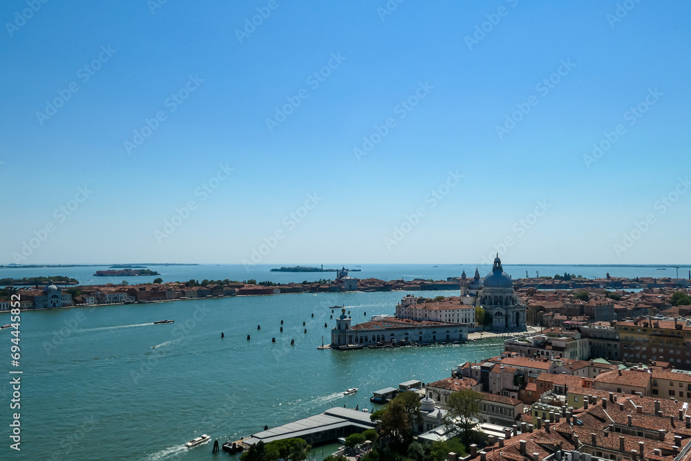 Aerial view from St Mark bell tower Campanile of the old town of Venice, Veneto, Italy, Europe. Looking at Basilica di Santa Maria della Salute. UNESCO World Heritage Site. Urban tourism in summer