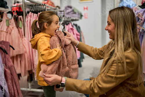 Foto The mom shows her daughter a piece of clothing she wants to buy, pressing it against her to check the size and envisioning how it will look