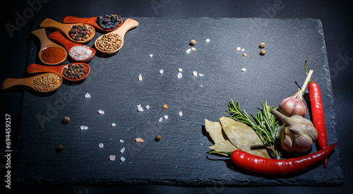 Many different spices and fresh vegetables for cooking on a black background, still life with vegetables and spices on a black background, ingredients for cooking