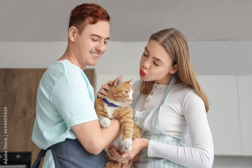 Young couple with cute cat in kitchen Young couple with cute cat in kitchen