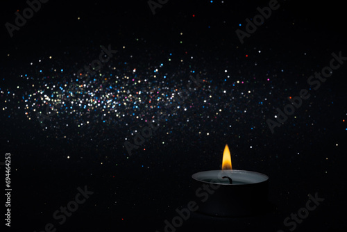 Candle flame with abstract bokeh background. One candle burns on a black shiny background