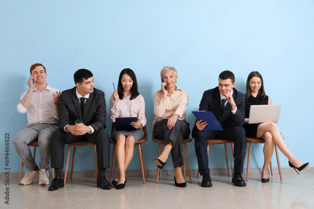 Applicants waiting for job interview near blue wall Applicants waiting for job interview near blue wall