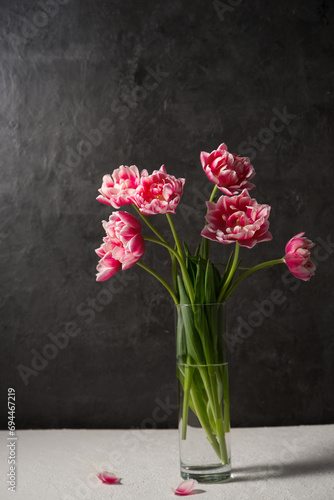 bouquet of pink terry tulips in a transparent glass vase on a dark background