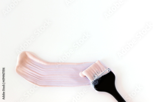Hair coloring brush with a smear of light paint on a white background.