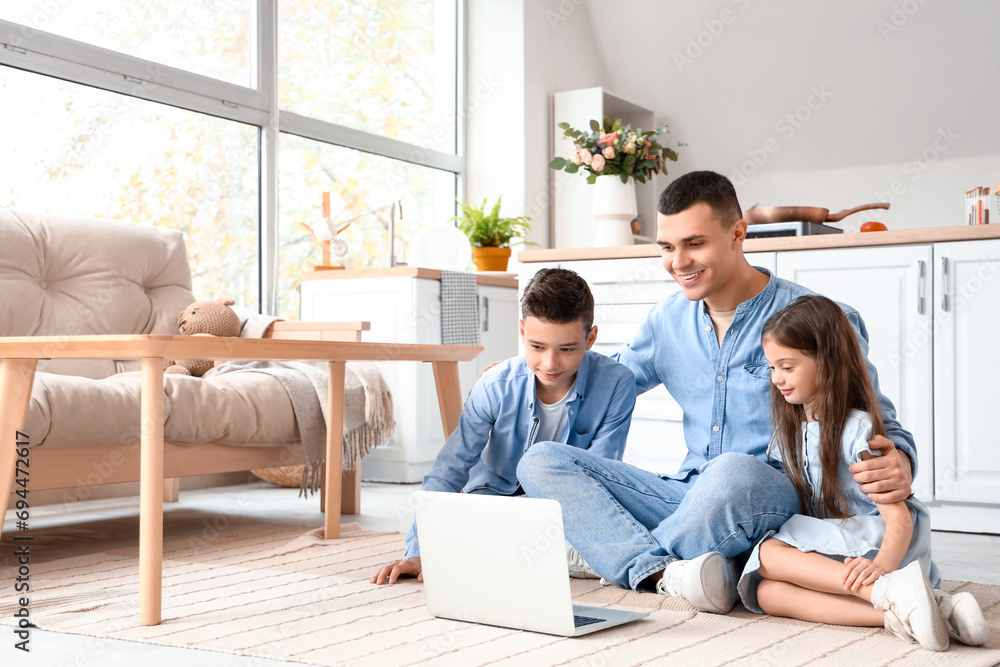 Little children with their father watching cartoons on laptop at home Little children with their father watching cartoons on laptop at home