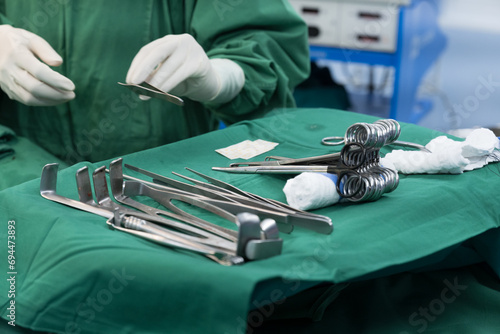 Surgeon doctor's hand with hygiene glove taking surgical clamps and medical equipment on green surgical tray inside operating room.Sterile surgical instrument tool equipment for surgery. photo