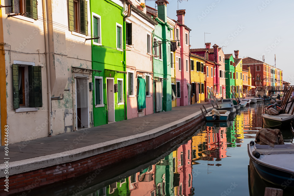Scenic view of bright colorful houses on island of Burano in city of Venice, Veneto, Northern Italy, Europe. Cruising around the Venetian Lagoon. Water canal along idyllic riverbank. Summer tourism
