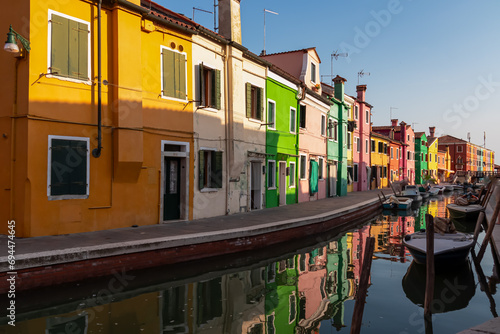 Scenic view of bright colorful houses on island of Burano in city of Venice, Veneto, Northern Italy, Europe. Cruising around the Venetian Lagoon. Water canal along idyllic riverbank. Summer tourism photo