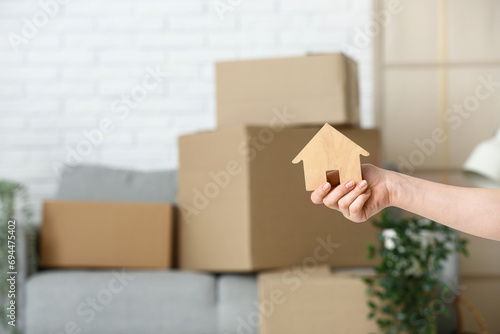 Woman with wooden house in room on moving day, closeup