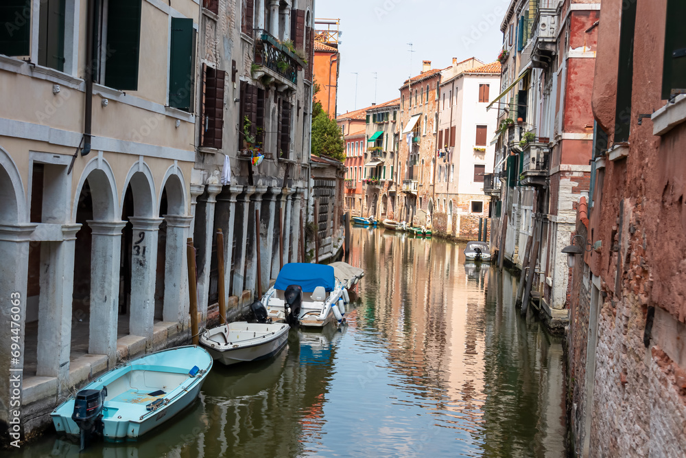 Panoramic view of a water channel in city of Venice, Veneto, Italy, Europe. Venetian architectural landmarks and old houses facades along the man made water traffic corridor. Urban tourism in summer