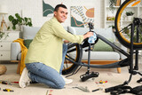 Young man wiping bicycle while repairing at home