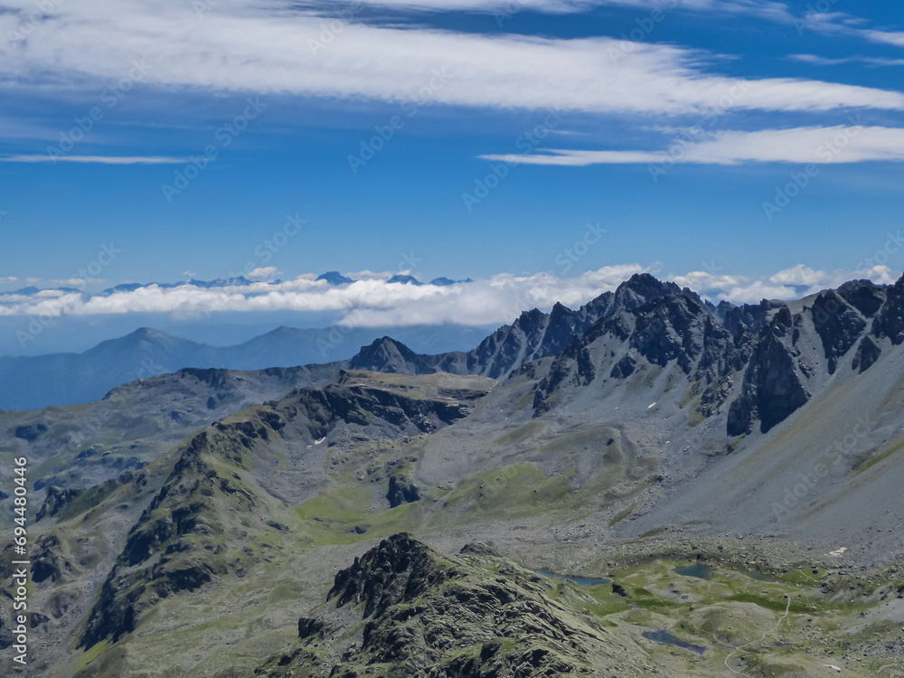 Scenic view from summit Viso Mozzo on mountain ranges of Cottian Alps, Cuneo, Piemonte, Italy, Europe. Hiking trail from Pian del Re. Massive rock walls and ridges in majestic landscape. Monte Viso