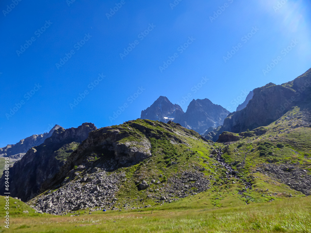 Alpine pasture with panoramic view of mountain summit Monte Viso (Monviso) in the Cottian Alps, Cuneo, Piemonte, Italy, Europe. Massive rock walls and ridges. Majestic landscape. Wanderlust, climbing