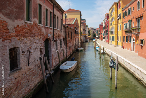 Panoramic view of a water channel in city of Venice, Veneto, Italy, Europe. Venetian architectural landmarks and old houses facades along the man made water traffic corridor. Urban tourism in summer